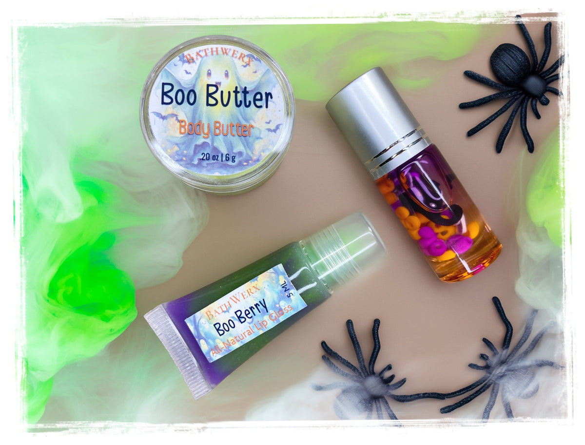 Halloween Boo Box contents: Boo Butter body butter, Boo Juice roll-on perfume, and Boo Berry lip gloss, styled with faux spiders and cobwebs.