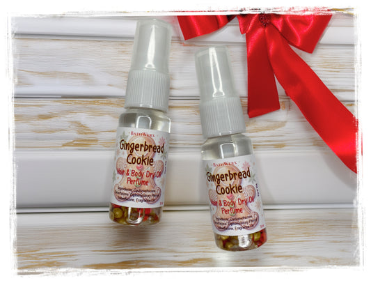 Two Gingerbread Cookie Hair & Body Dry Oil Perfume spray bottles on white wood beside a red holiday bow.