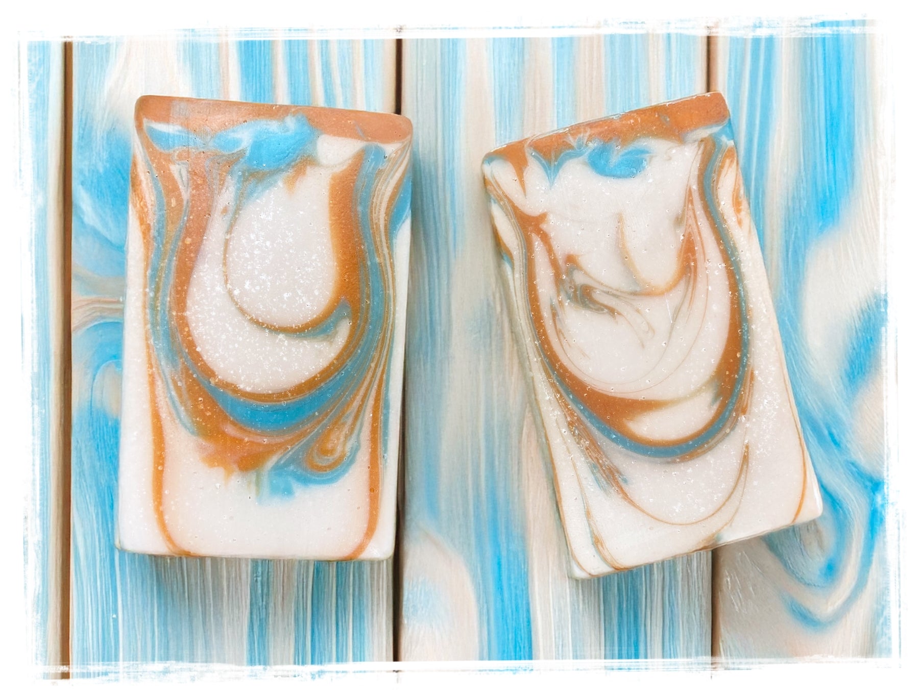 Two rectangular soap bars with marbled design on a striped background. Handcrafted Artisan Soap: Sunshine Warrior