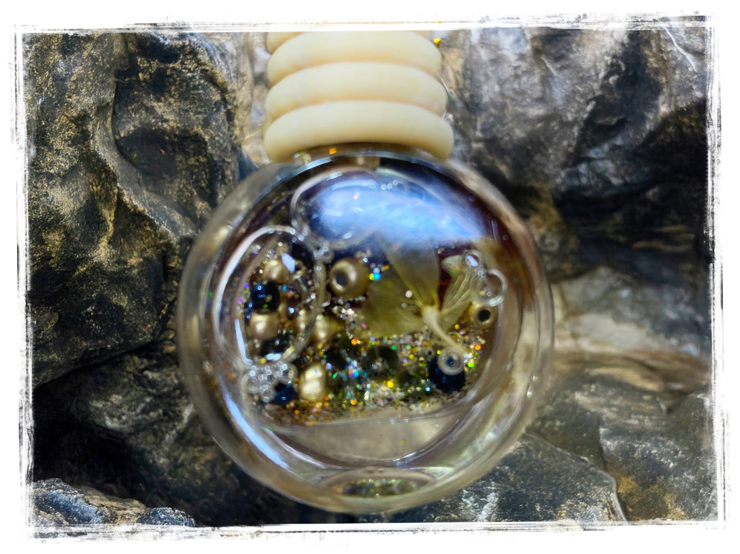 Masculine scented car charm close-up showing glass sphere with decorative beads on stone surface