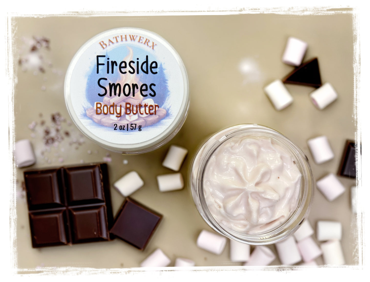 BathWerx Fireside S'mores Body Butter 2 oz jar with lid displayed next to an open jar of whipped body butter, surrounded by dark chocolate pieces and mini marshmallows on a neutral background