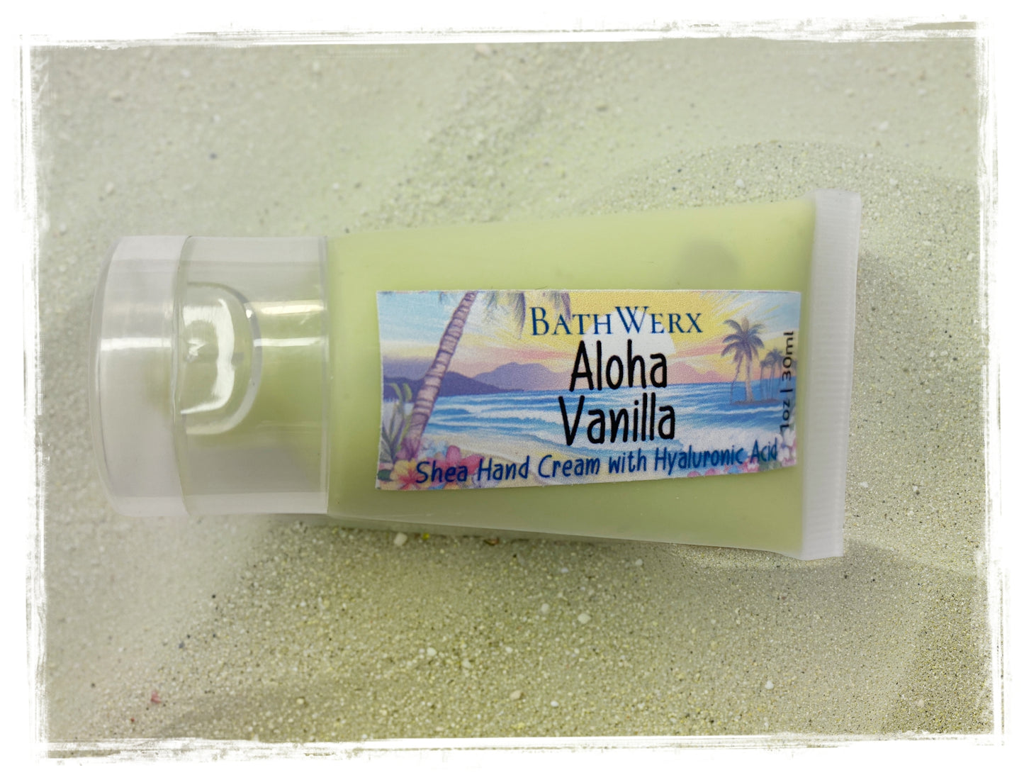 BathWerx Aloha Vanilla Shea Hand Cream tube resting on sandy beach surface