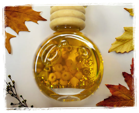 Pumpkin Honey Chai car charm – round glass bottle with golden amber oil and orange beads on white background