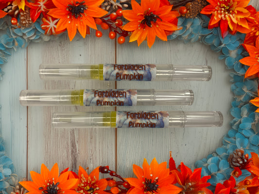 Three Forbidden Pumpkin Nail & Cuticle Repair Pens arranged on a rustic white wood surface, surrounded by vibrant orange and blue fall flowers with pine cones and red berries