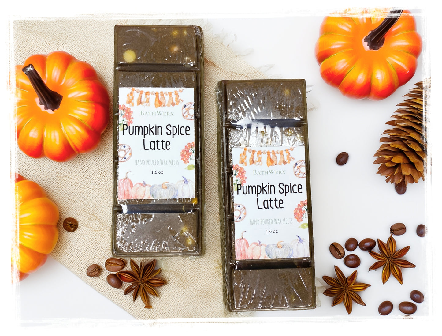 Two BathWerx Pumpkin Spice Latte hand-poured wax melts in deep espresso brown, displayed on a white marble and burlap surface surrounded by orange decorative pumpkins, a pine cone, coffee beans, and star anise.