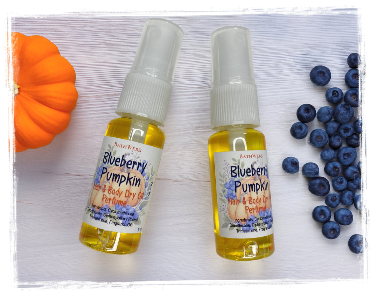BathWerx Blueberry Pumpkin Hair & Body Dry Oil Perfume, two 15ml spray bottles filled with golden oil, displayed with a mini orange pumpkin and fresh blueberries on a white wood surface.