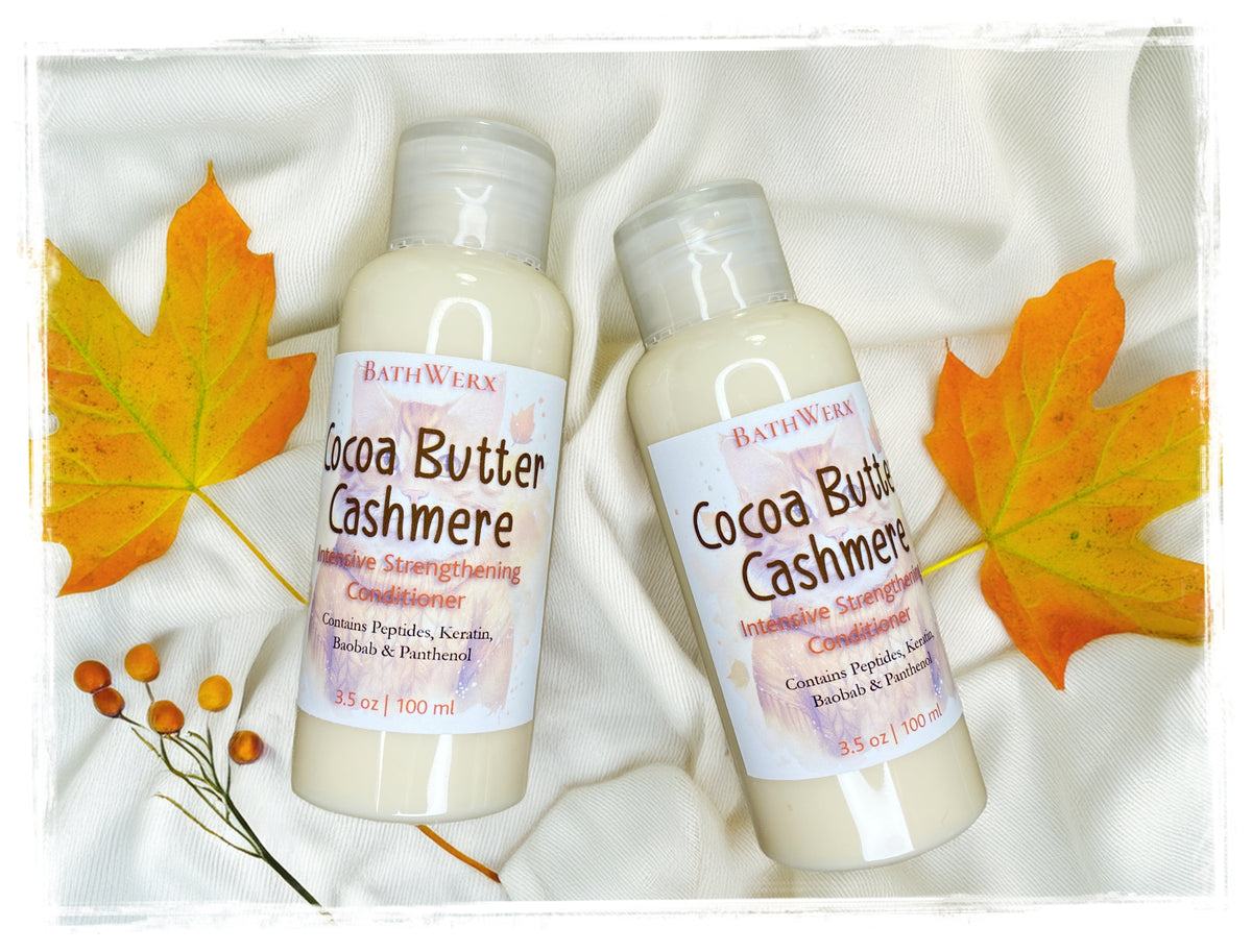 BathWerx Cocoa Butter Cashmere Intensive Strengthening Conditioner, two 3.5 oz bottles with Peptides, Keratin, Baobab and Panthenol, surrounded by fall maple leaves on a white knit background.