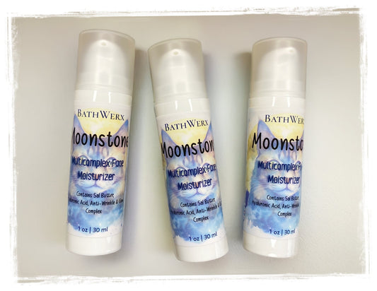 Three bottles of BathWerx Moonstone Face Moisturizer on a tan background.