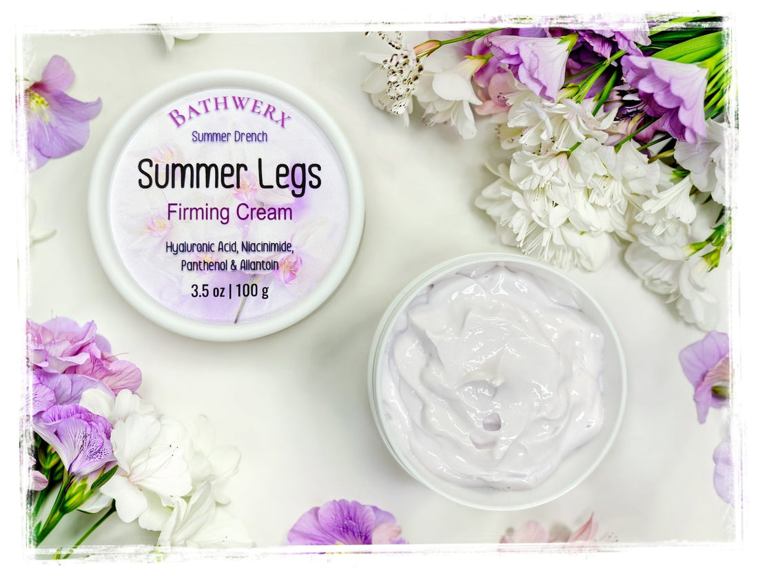 BathWerx Summer Legs Firming Cream jar open with lid beside it, surrounded by purple and white flowers on a white background