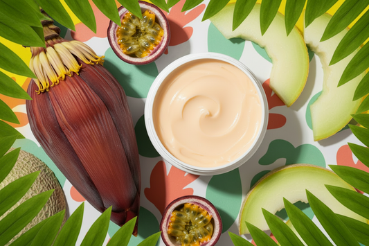 Tub of light orange body butter cream with tropical fruits and lush green leaves on a sunny yellow background – BathWerx Summer Legs Firming Cream