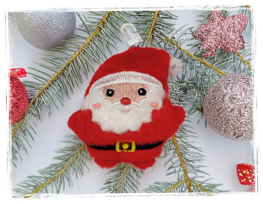 Red and white Santa plush Christmas keychain on evergreen branches.