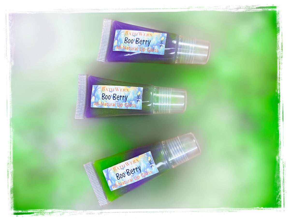 Boo Berry all-natural lip gloss tubes with clear caps, arranged on a soft green background.