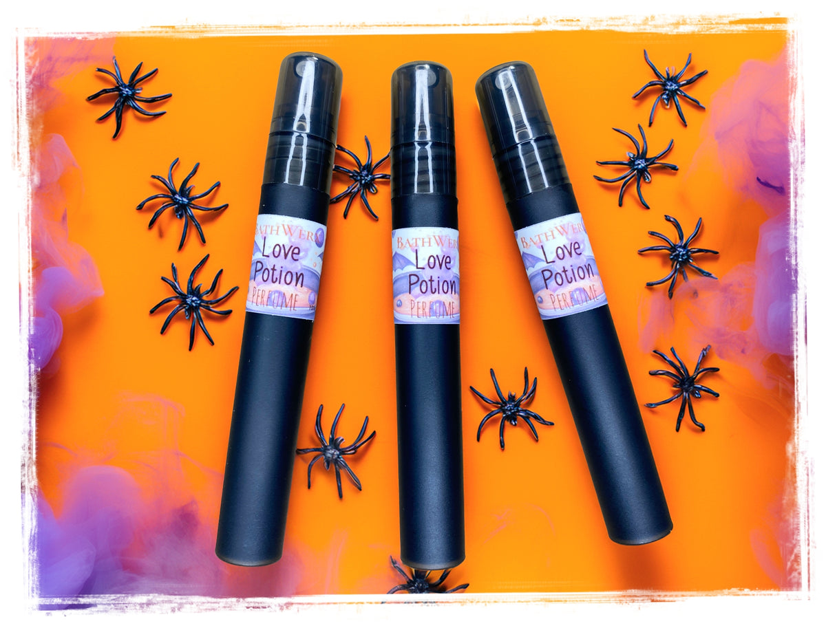 Love Potion Halloween perfume sprays by BathWerx on an orange and purple background with black spider decorations.