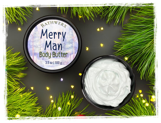 Merry Man body butter in an open black jar with white cream, beside its labeled lid and surrounded by pine branches and holiday lights.