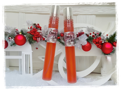 Two Candy Cane Cloud perfume spray bottles with silver caps against festive greenery, red ornaments, and a white holiday backdrop.