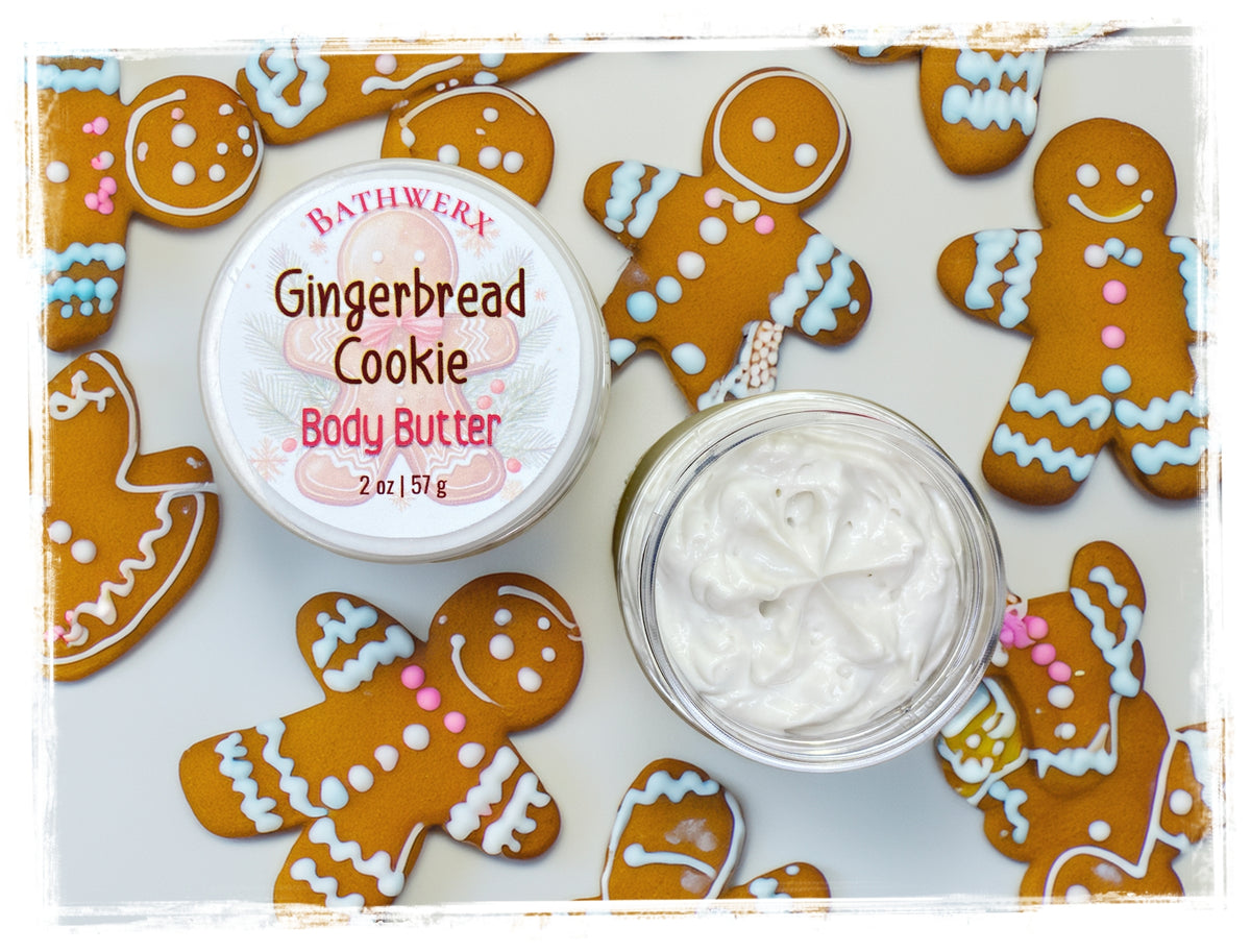 Open jar of Gingerbread Cookie Body Butter with its labeled lid beside it, surrounded by decorated gingerbread cookies.