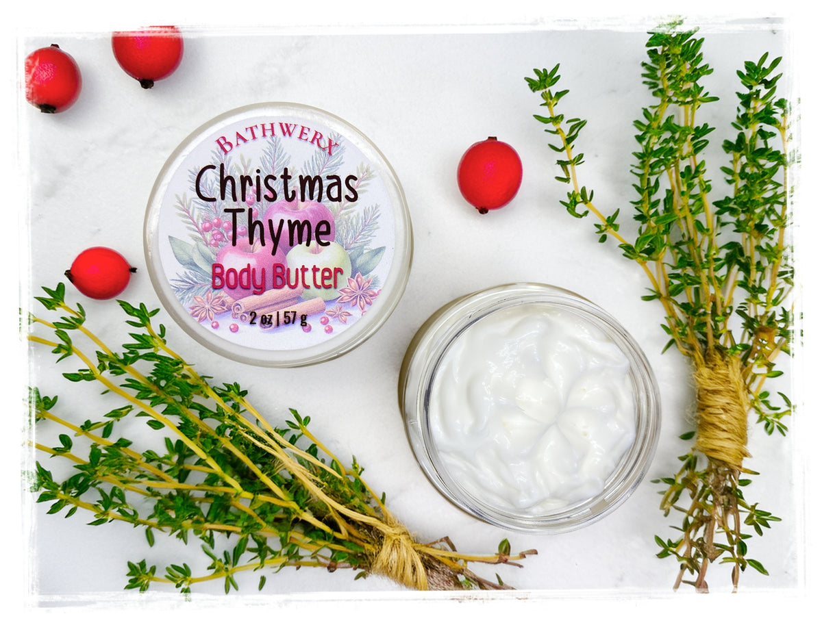 Open jar of Christmas Thyme body butter with white cream, labeled lid, fresh thyme sprigs, and red berries.
