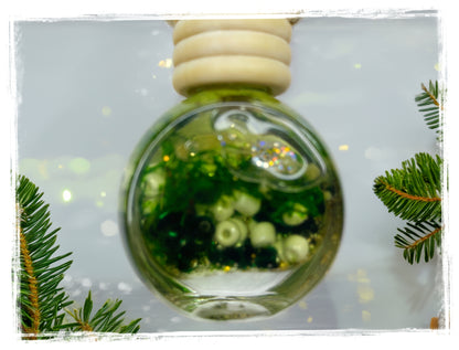 Winter Spruce car charm in a round glass bottle with green and cream beads and a wooden cap.