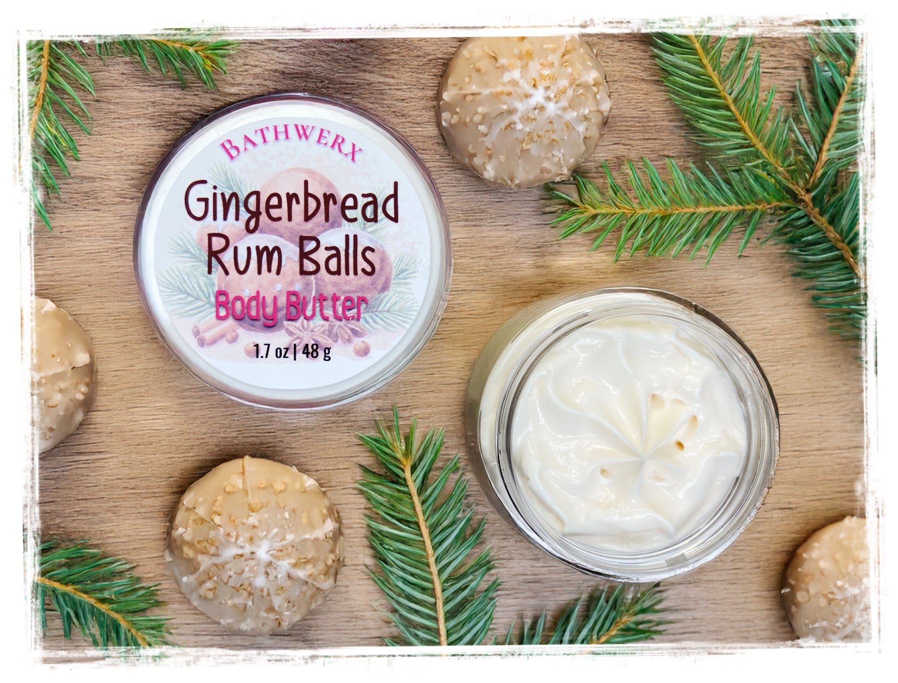 Bath and body product with gingerbread rum balls packaging on a wooden surface with greenery.