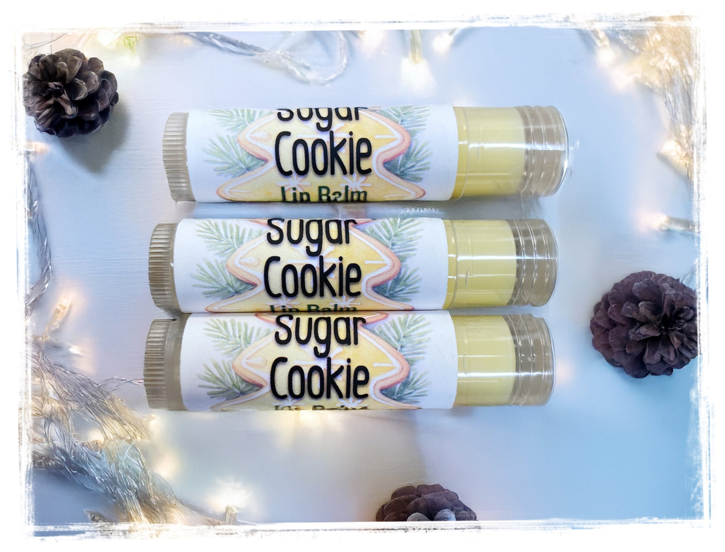 Three lip balms labeled 'Sugar Cookie' on a light blue background with decorative elements.