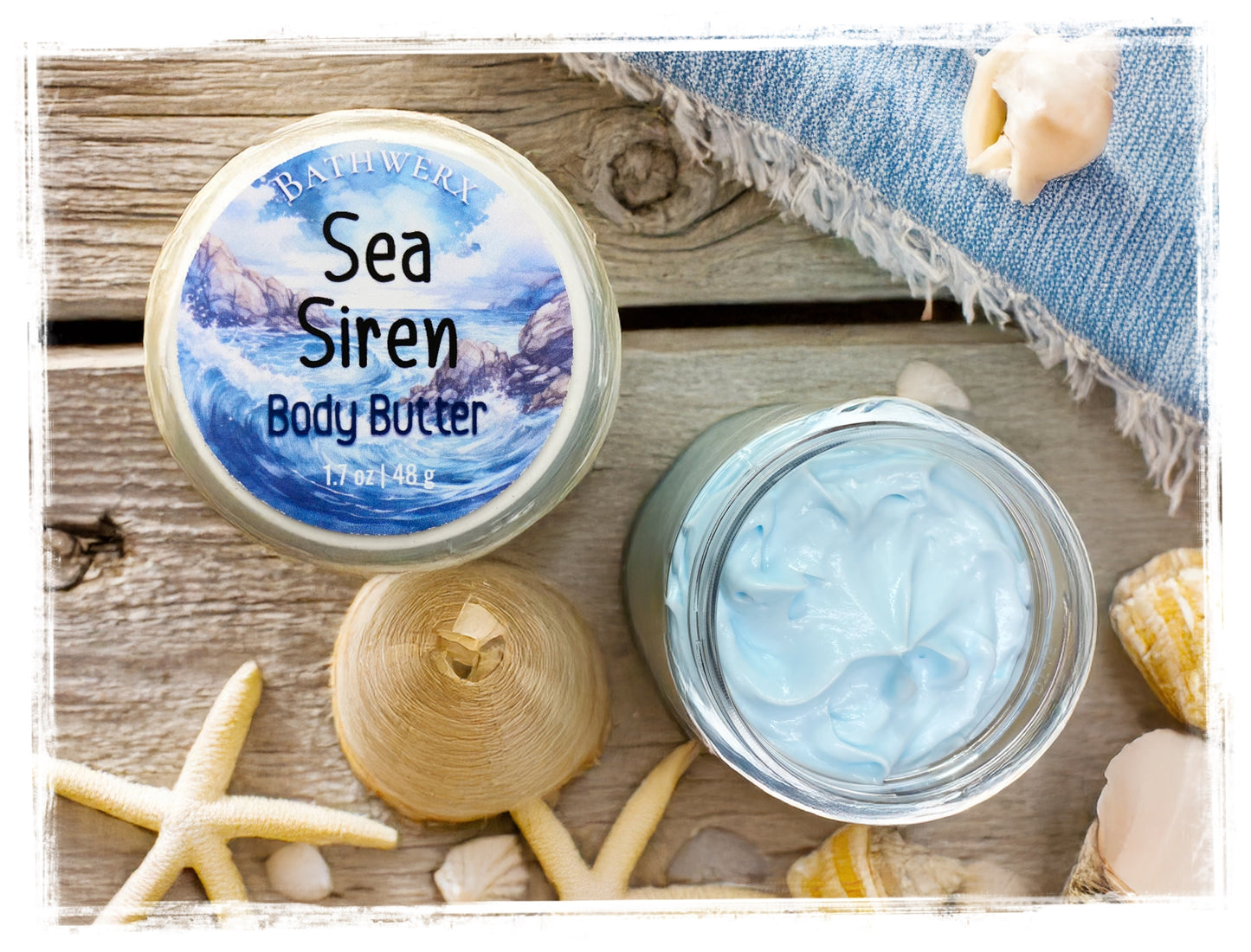 Sea Siren body butter jar with lid off on a wooden surface with shells and starfish.