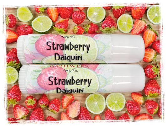 Two tubes of BathWerx Strawberry Daiquiri Lotion Perfume sticks on a background of strawberries and limes.