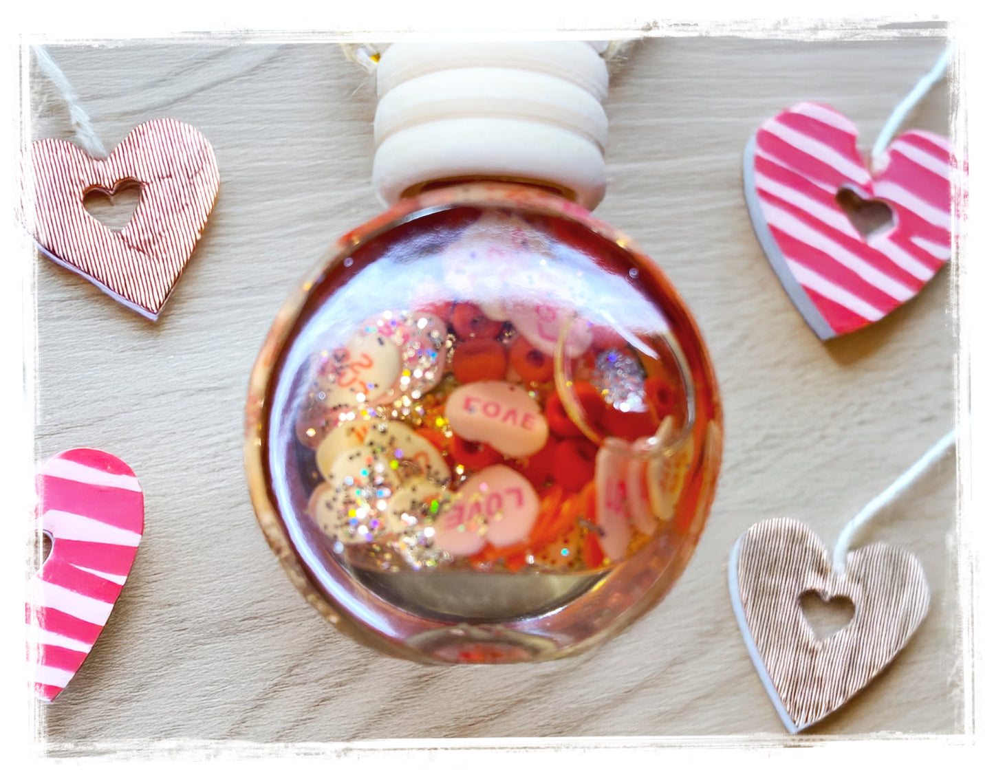 Decorative black cherry car charm with heart-shaped objects on a wooden surface