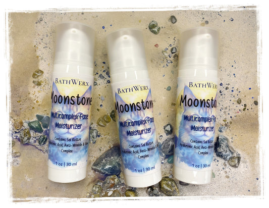 Three bottles of Bathwerx Moonstone Multi Complex Face Moisturizer on a textured beige background.