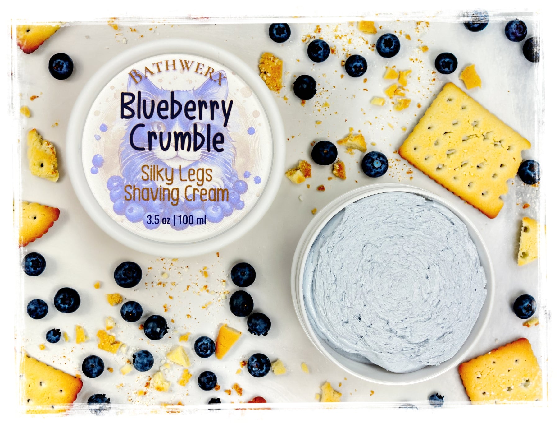 BathWerx Blueberry Crumble Silky Legs Shaving Cream in a white jar, 3.5 oz, surrounded by fresh blueberries and crumbled shortbread cookies on a white surface