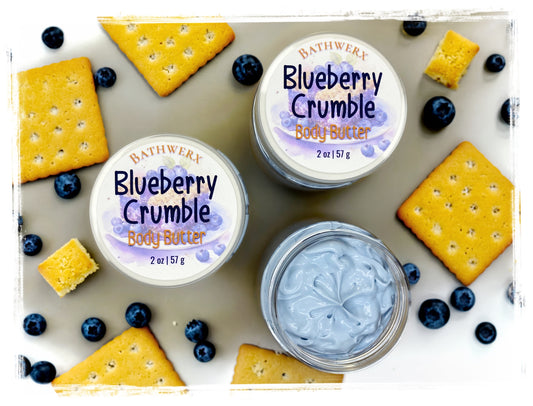 Two jars of BathWerx Blueberry Crumble Body Butter with fresh blueberries and golden crackers, one open to reveal a lavender whipped texture.