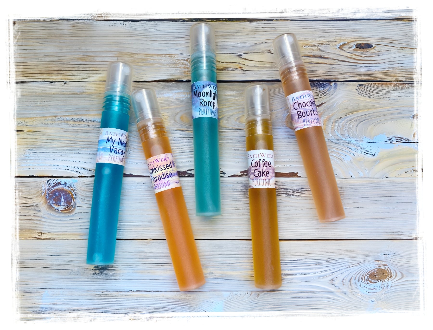 BathWerx perfume spray pens arranged on a rustic white wood surface