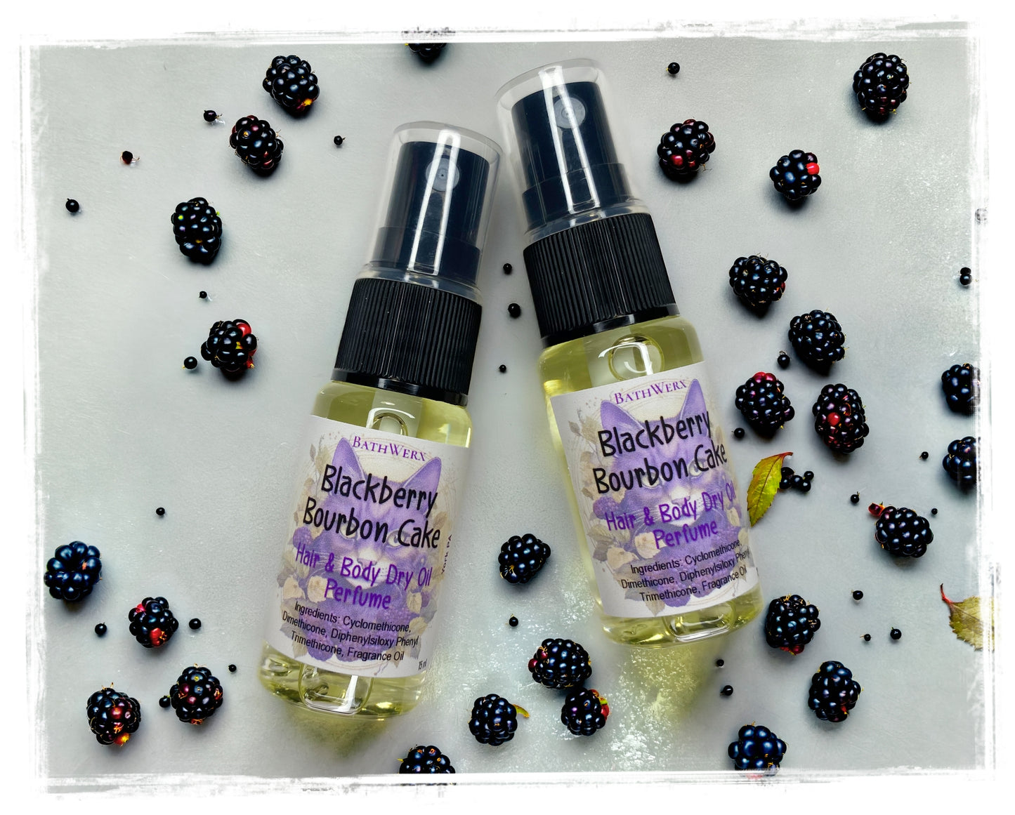 BathWerx Blackberry Bourbon Cake Hair and Body Dry Oil Perfume, two 15ml spray bottles surrounded by fresh blackberries on white surface