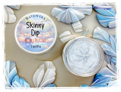 BathWerx Skinny Dip Body Butter open clear jar showing creamy white texture, surrounded by blue and white paper fan decorations