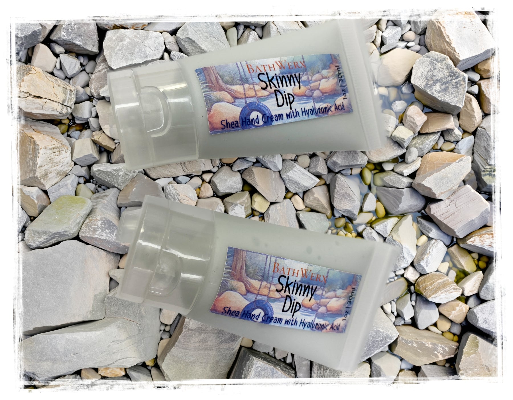 BathWerx Skinny Dip Shea Hand Cream two frosted tubes resting on natural river rocks