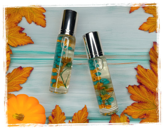 Forbidden Pumpkin Fall Roll-On Perfume Oil with turquoise beads and orange botanicals in glass roller bottles styled with autumn leaves and pumpkin
