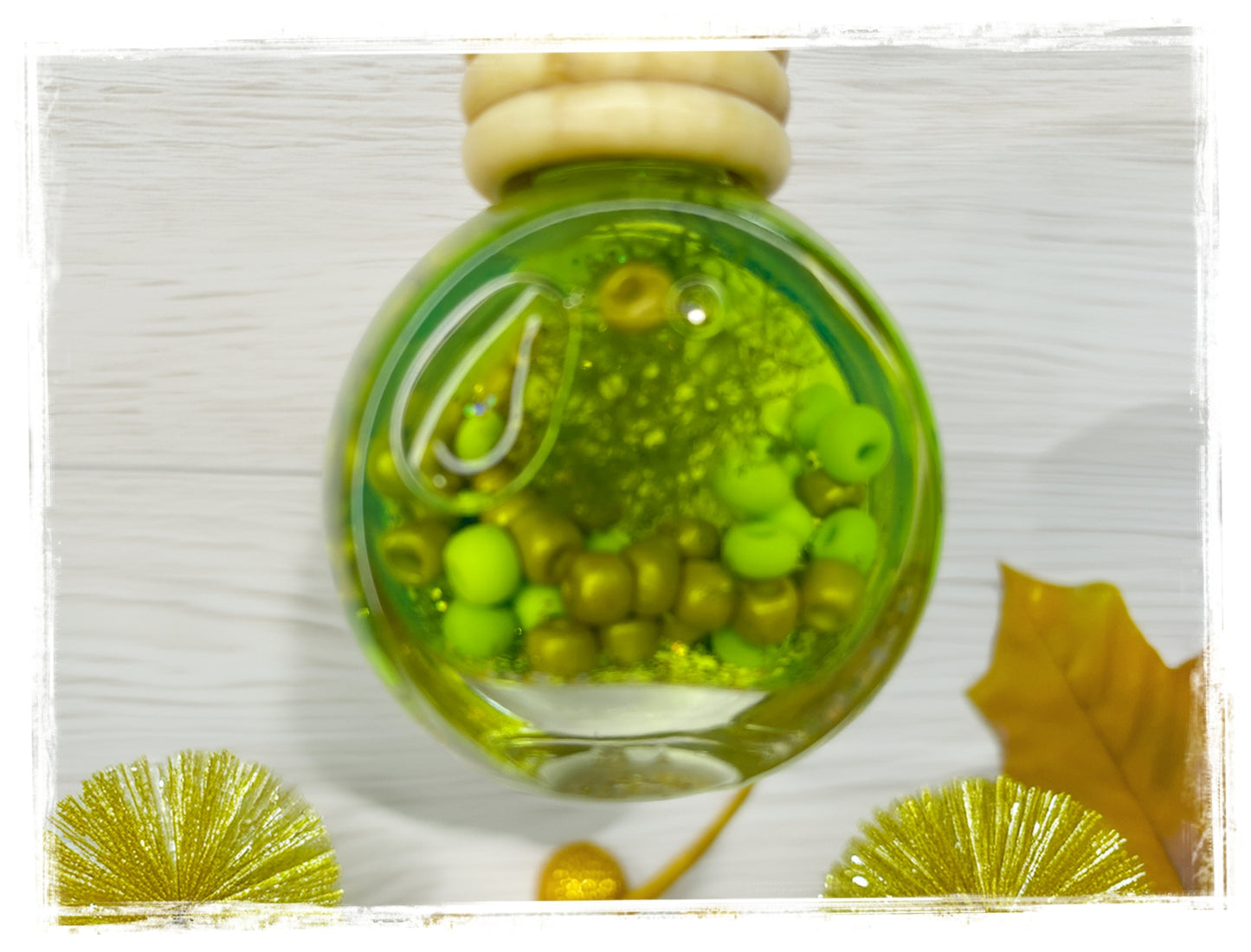 Apple Cider Donut Fall Scented Car Charm with green oil and mixed beads in a round glass bottle styled with gold botanicals and autumn leaf
