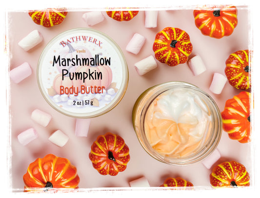 BathWerx Vanilla Marshmallow Pumpkin Body Butter 2 oz jar with swirled orange and white whipped texture, surrounded by mini pumpkins and pastel marshmallows on a blush pink background