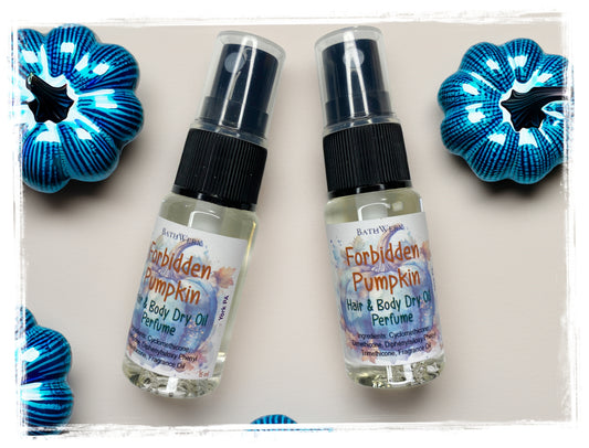 Two BathWerx Forbidden Pumpkin Hair & Body Dry Oil Perfume spray bottles with clear glass and black pump tops, surrounded by decorative blue metallic pumpkins on a neutral background