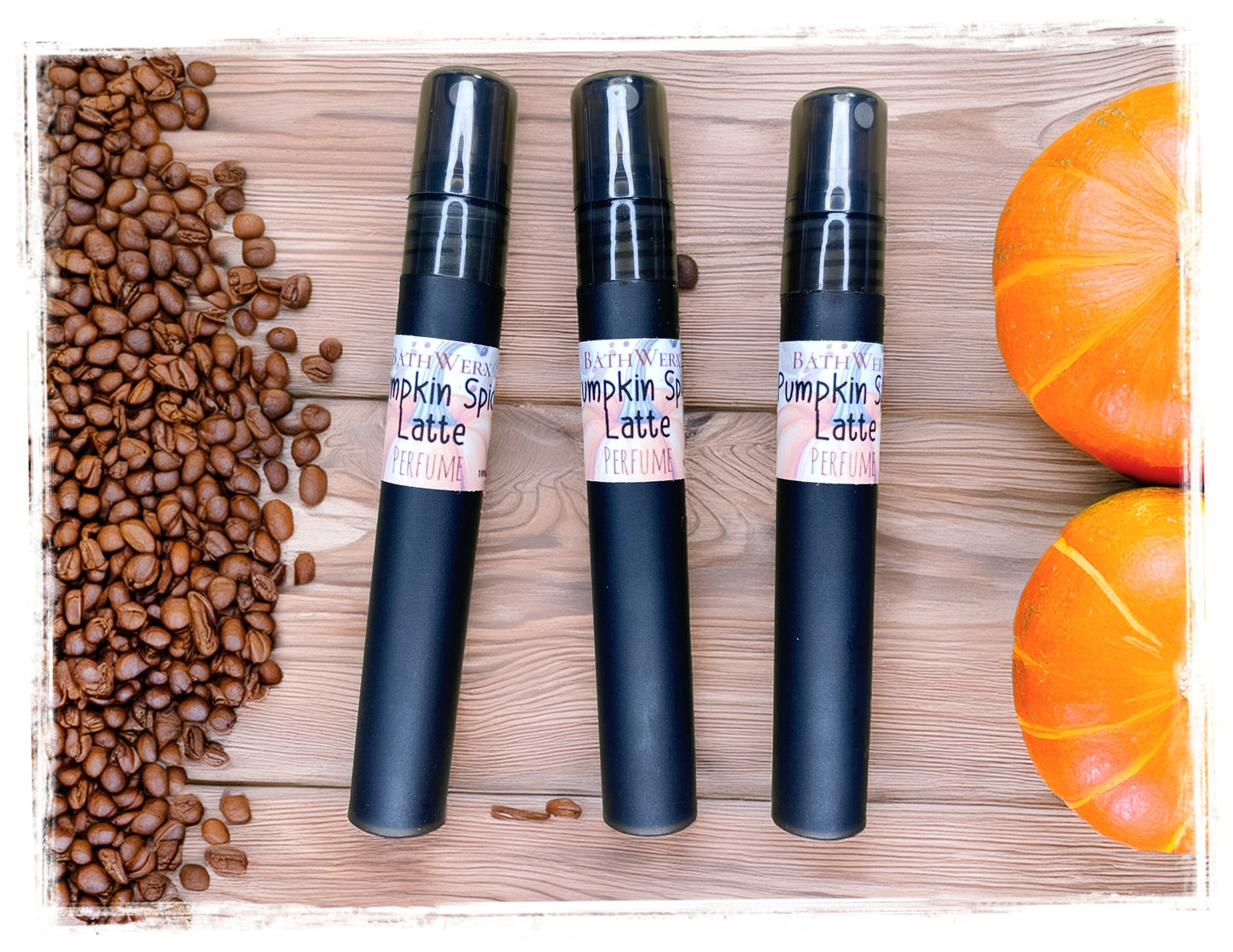 BathWerx Pumpkin Spice Latte perfume sprays in matte black, styled on a rustic wood surface with scattered coffee beans and orange pumpkins - travel-size 10ml fall fragrance