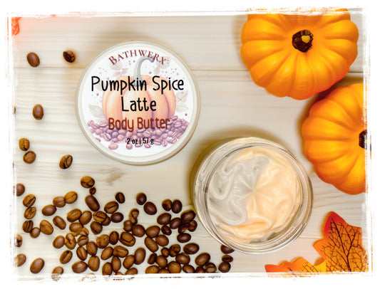 BathWerx Pumpkin Spice Latte Body Butter 2 oz jar open to show swirled cream texture, with coffee beans, orange pumpkins, and fall leaves on a white wood surface