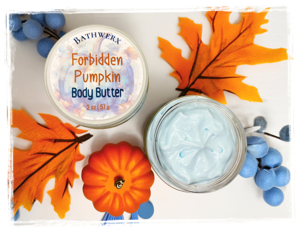Flat lay of BathWerx Forbidden Pumpkin Body Butter 2 oz jar — lid labeled and open jar showing light blue whipped cream texture, styled with orange autumn leaves, a mini pumpkin, and blue berry accents.