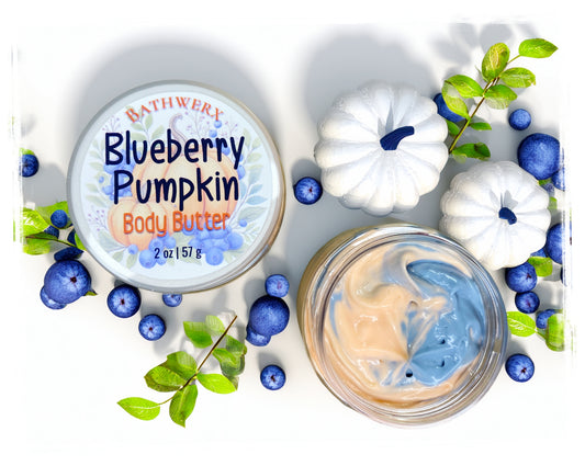 BathWerx Blueberry Pumpkin Body Butter, 2 oz jar shown open with a peach and blue swirled body butter, displayed with white decorative pumpkins, fresh blueberries, and green leaves on a white surface.