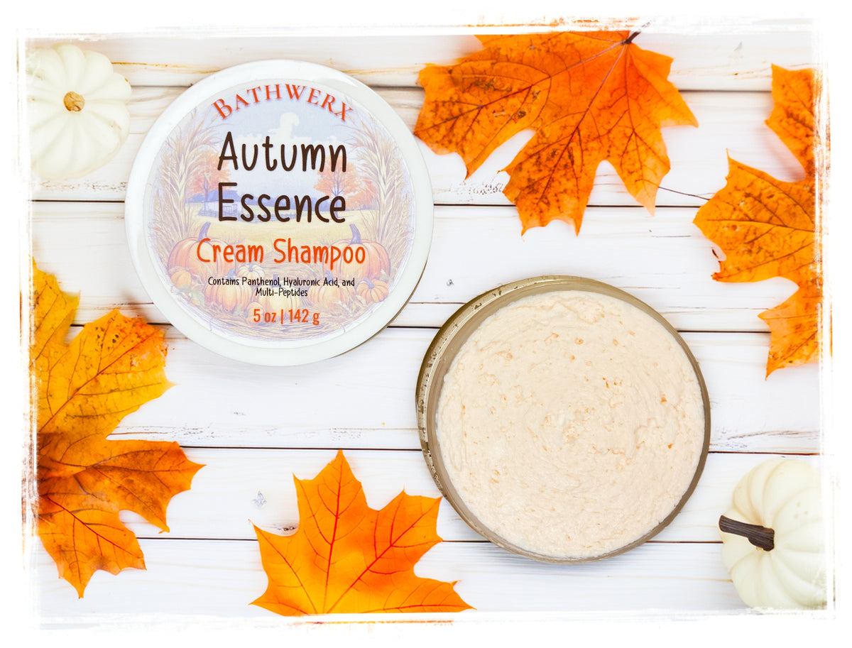 BathWerx Autumn Essence Cream Shampoo 5 oz jar open to reveal cream texture, with orange fall maple leaves and white pumpkins on white wood.